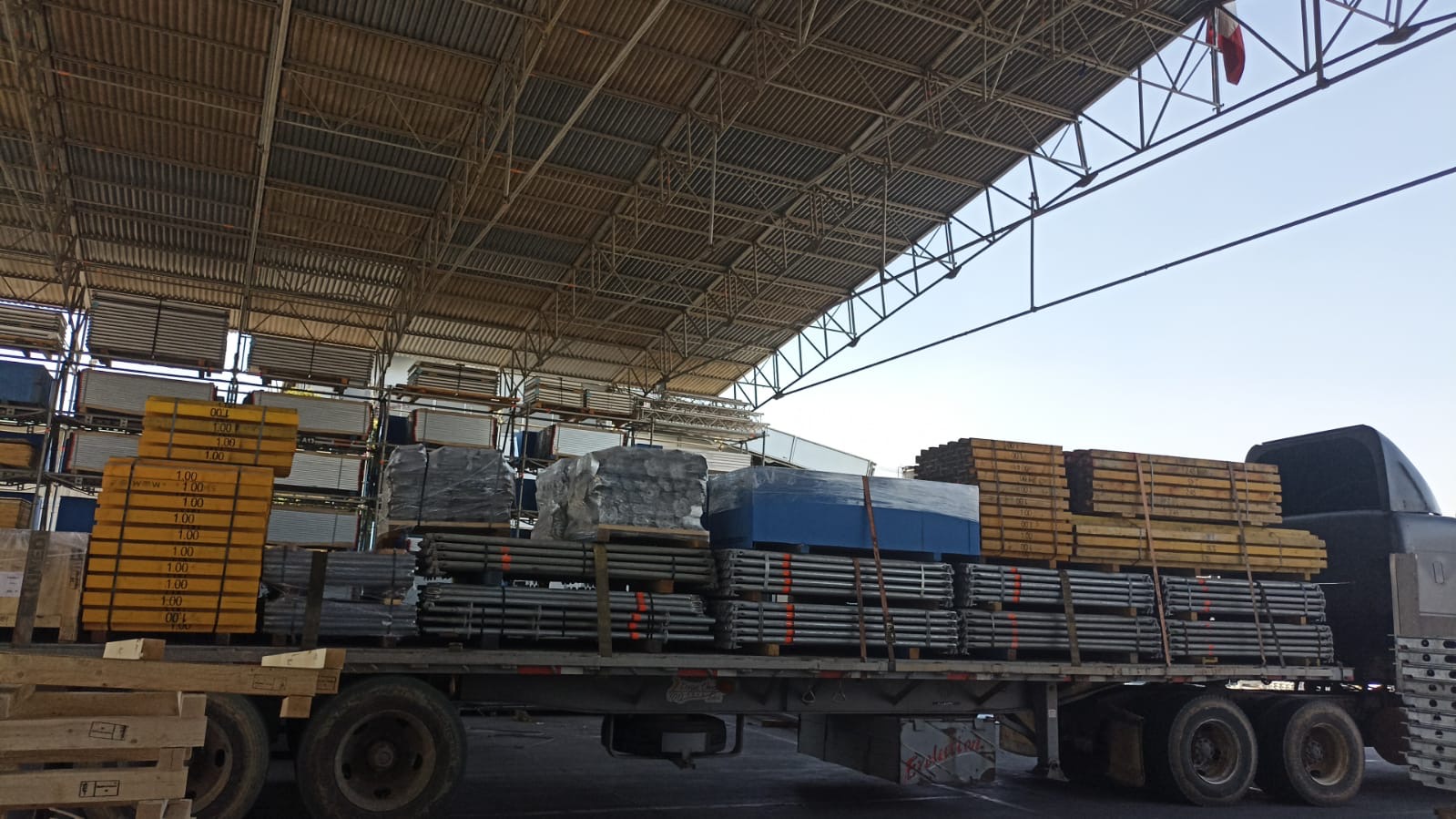 Materiales industriales y perfiles metálicos asegurados sobre plataforma